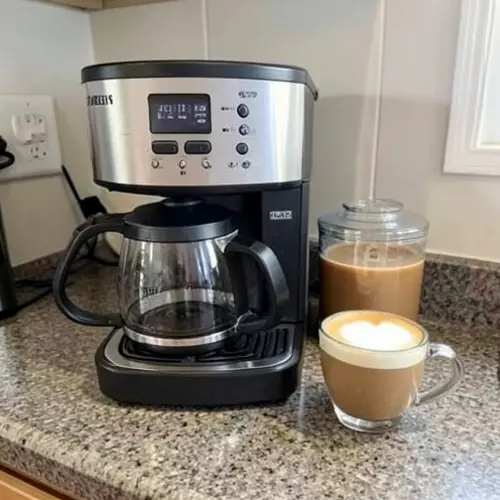Cómo elegir una cafetera para latte y cappuccino en casa con cafetera doméstica, jarra de leche y dos bebidas sobre encimera real