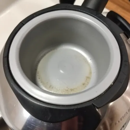 Detalle de filtro desmontable y fondo liso de un hervidor con restos leves de cal listos para una limpieza sencilla