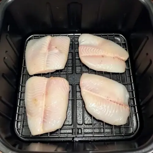 Cesta de freidora con filetes de pescado bien separados y superficie fácil de limpiar tras una cocción doméstica
