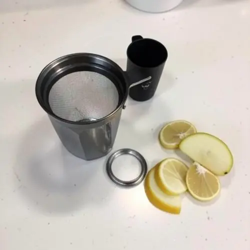 Licuadora desmontada con malla limpia, piezas secas y fruta cortada para probar si recupera rendimiento en casa