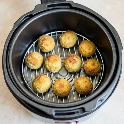 Cesta de freidora con una porcion de pizza y varias croquetas bien separadas para recalentar sin reblandecer